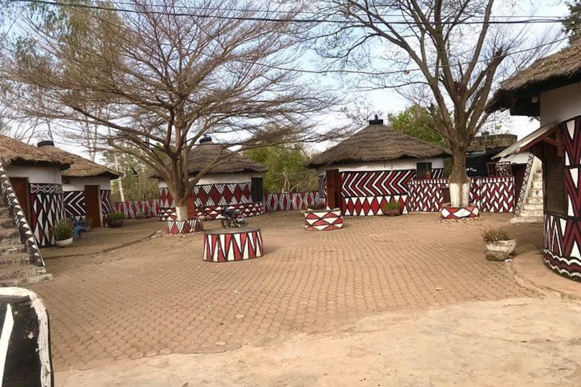 A village with thatched-roof huts, patterned walls, and a paved courtyard. 4
