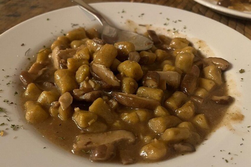 Une assiette de gnocchis nappés d’une sauce brune, qui contient peut-être des champignons, le tout servi dans une assiette blanche. 3