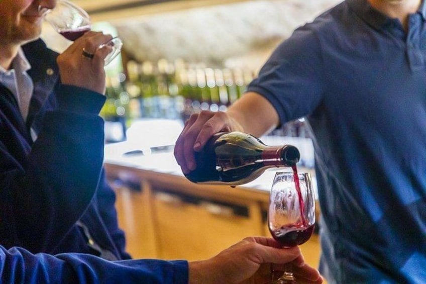 A person pouring red wine into a glass. 5