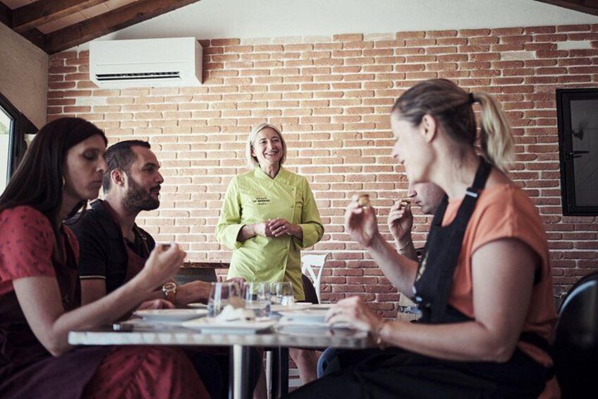 A group of people sitting at a table in a brick-walled room, engaged in conversation and eating. 1