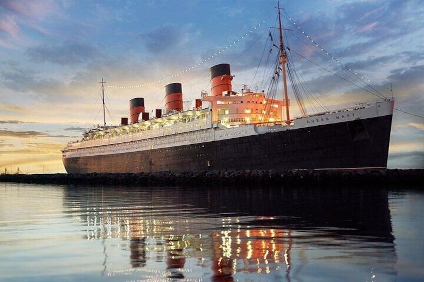 A large ship named 'Queen Mary' docked at a pier with its reflection visible on the water. 2