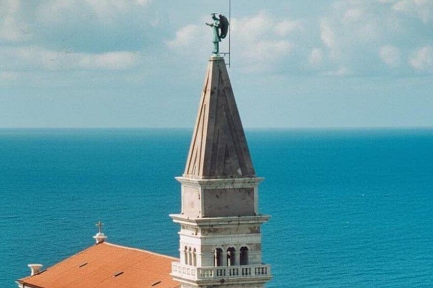A coastal church with a bell tower and a statue on top. 4