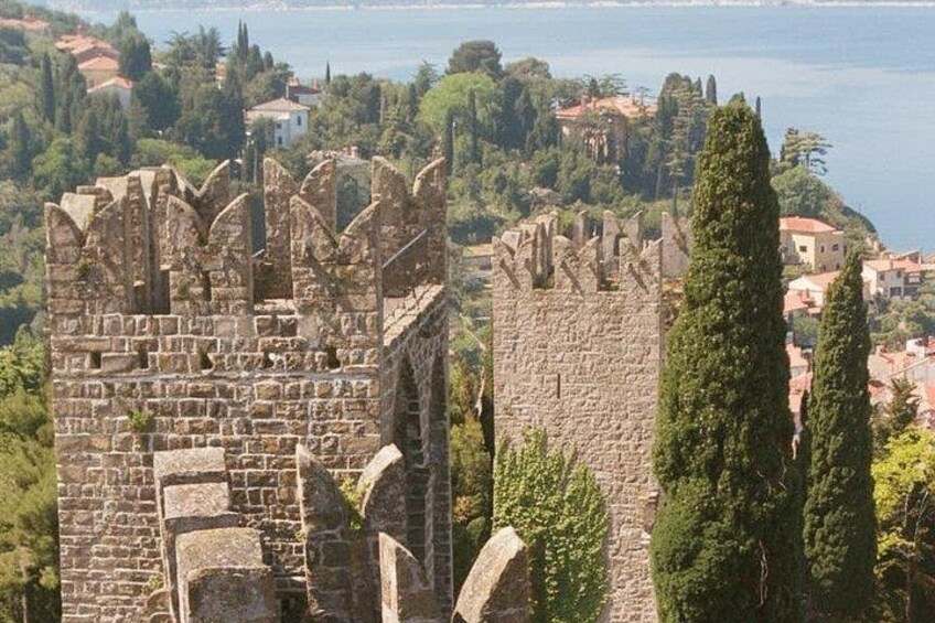 A stone castle with battlements overlooking a coastal town. 3