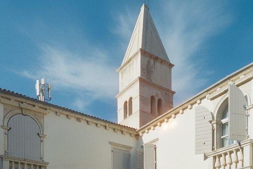 A white building with a bell tower and arched windows. 2