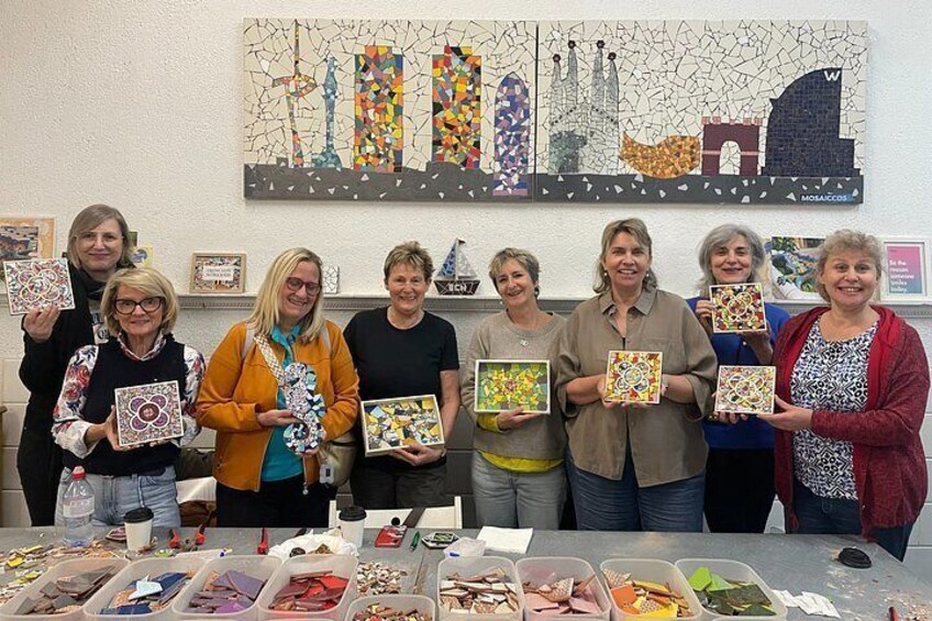 A group of people holding patterned tiles, with a table of various materials in front of them. 2