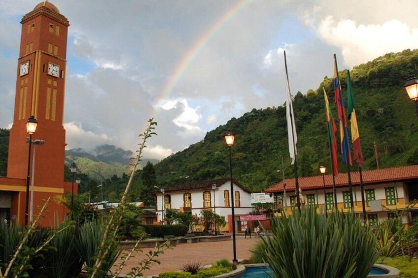 A clock tower, a rainbow, flags, and a mountainous landscape. 2