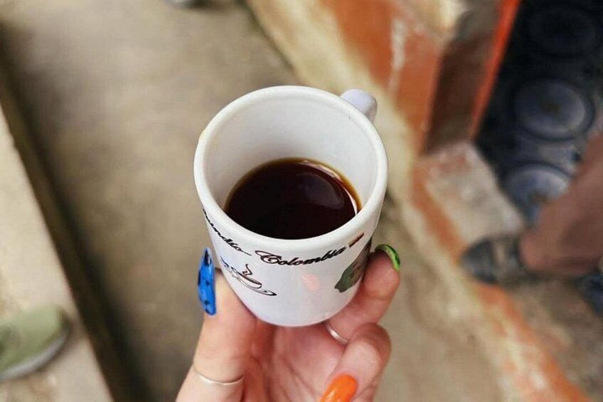 A hand holding a white mug with a design, containing a dark liquid, possibly coffee or tea. 4