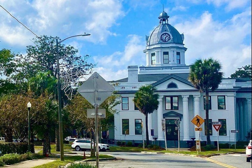 A large white building with a dome and clock tower, surrounded by palm trees and a clear blue sky. 5