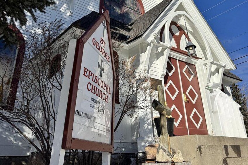 A church sign for St. George Episcopal Church with a red door and white trim. 3