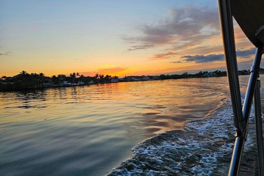 A sunset over a calm body of water with a boat's wake visible. 5
