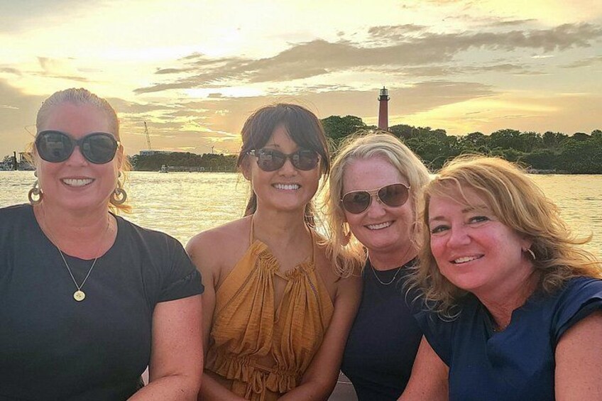 Four people standing by a body of water with a lighthouse in the background. 3