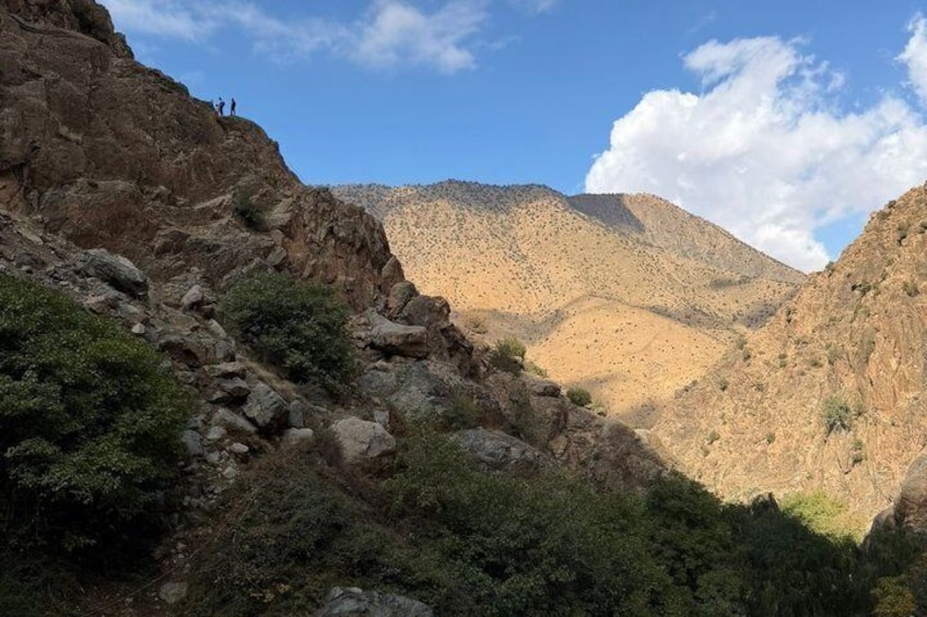A rocky canyon with sparse vegetation and a clear sky. 3