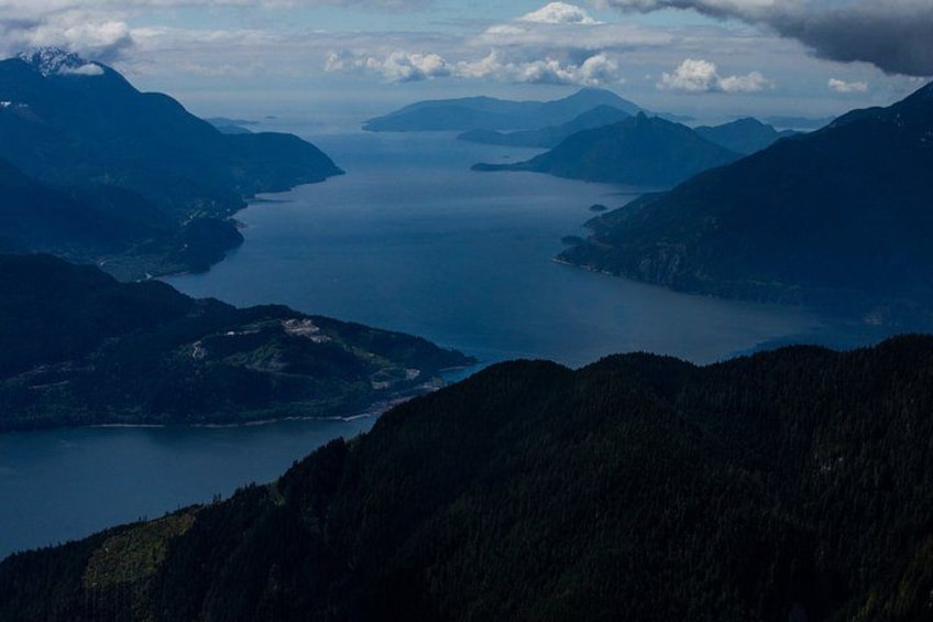 Un paysage montagneux avec une vaste étendue d’eau entourée de zones boisées. 2