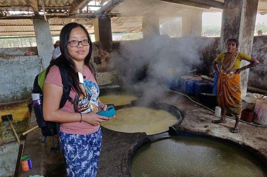 A person standing near a large outdoor cooking area with steam rising, surrounded by concrete structures. 2