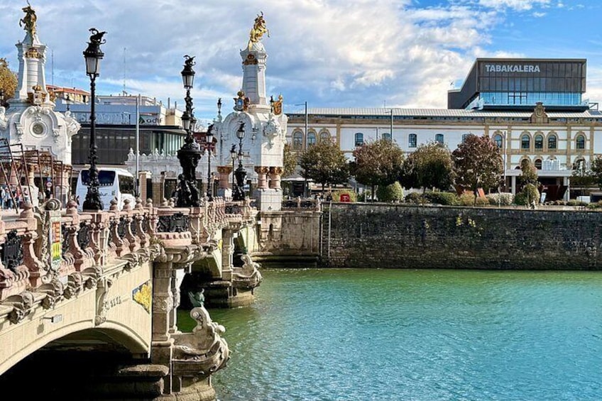 A bridge with ornate statues, a river, and a building labeled 'TABAKALERA' in the background. 4