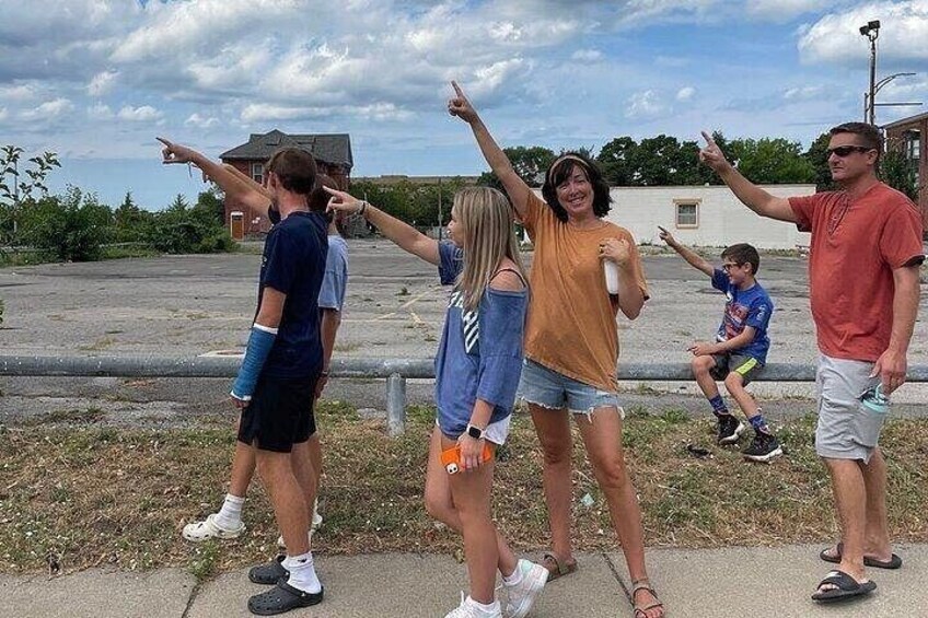 A group of people standing outdoors, some pointing in different directions. 2