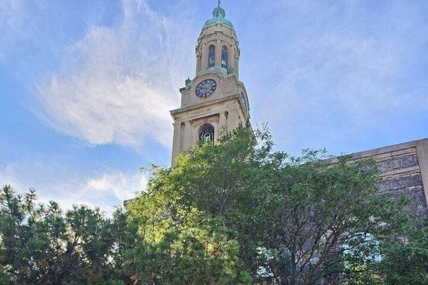 A clock tower with a clock face, surrounded by trees and a clear sky. 1