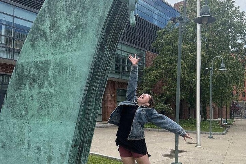 A person interacting with a large green sculpture in an urban setting. 2