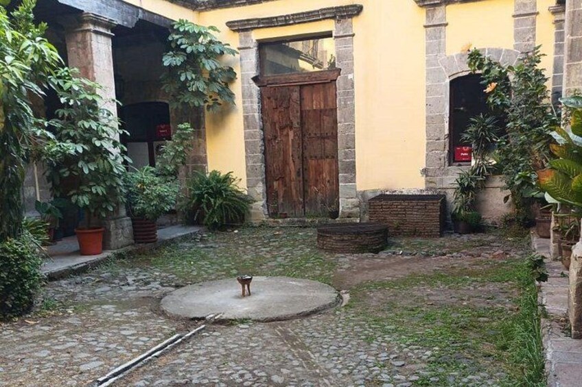Un patio con piso de adoquines, una puerta de madera y plantas en macetas. 2