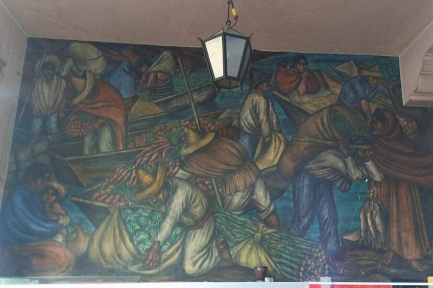 Un mural con gente en barcas, un farol y una escena de mercado. 4