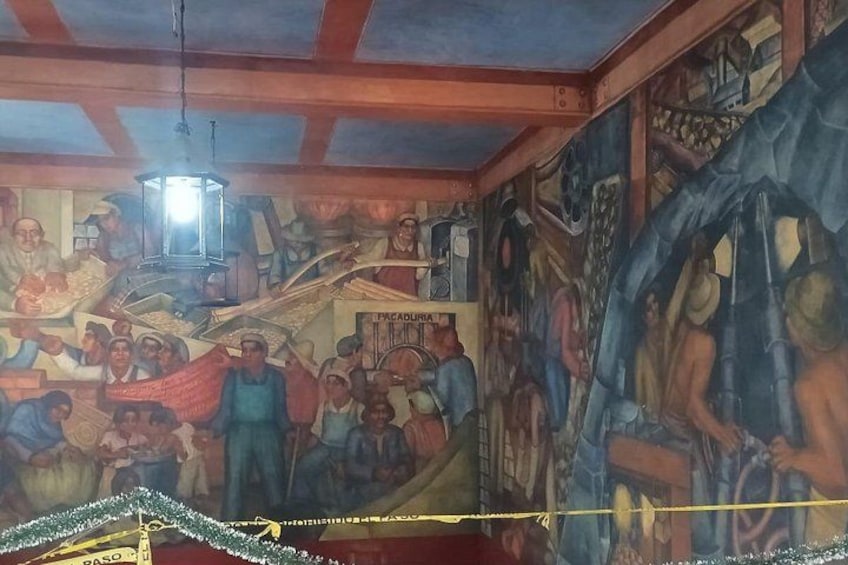 Un mural con diversas figuras y escenas, incluyendo un farol colgando del techo. 5