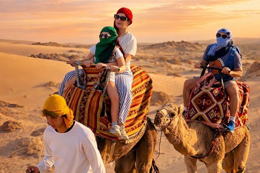 Tres personas montando camellos en un paisaje desértico. 1