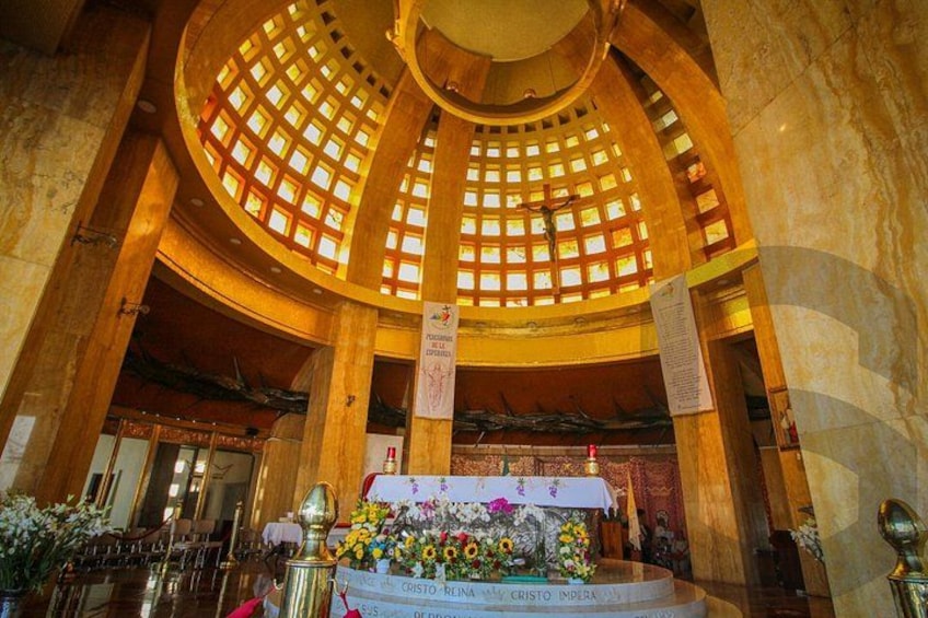 A grand hall with a domed ceiling, a central altar adorned with flowers, and a large chandelier. 2