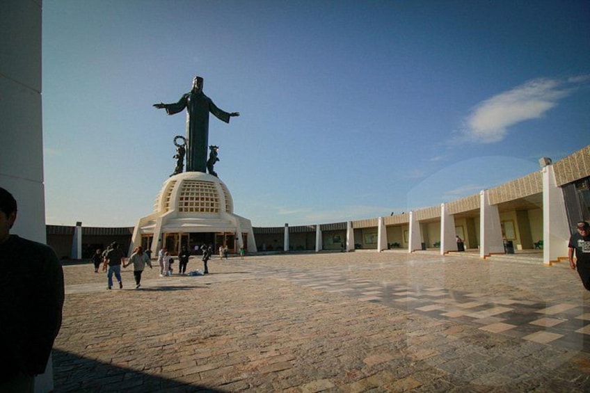 A plaza with a large statue, people walking, and a building with columns. 5
