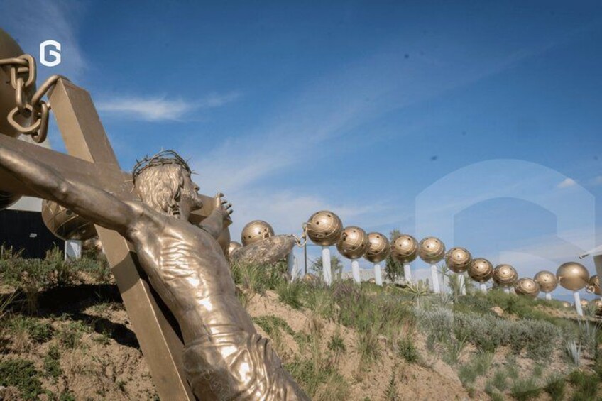 A golden statue of a figure with outstretched arms, a series of golden spheres, and a desert landscape. 5