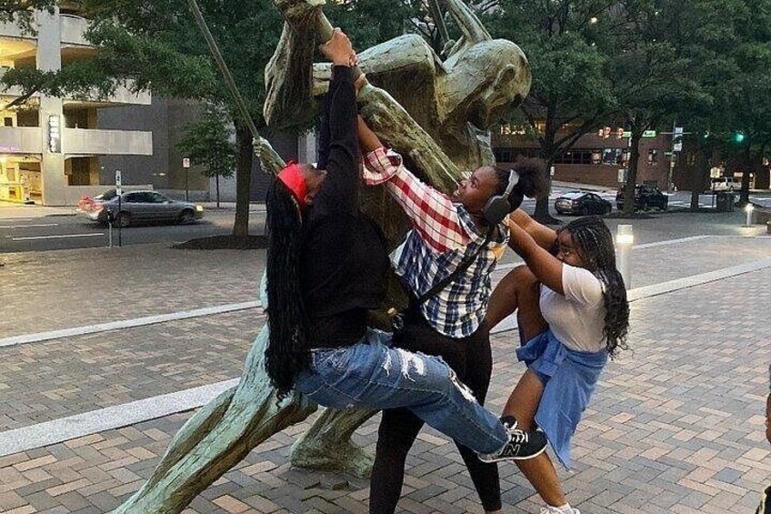 A sculpture of a large animal with people interacting with it. 5