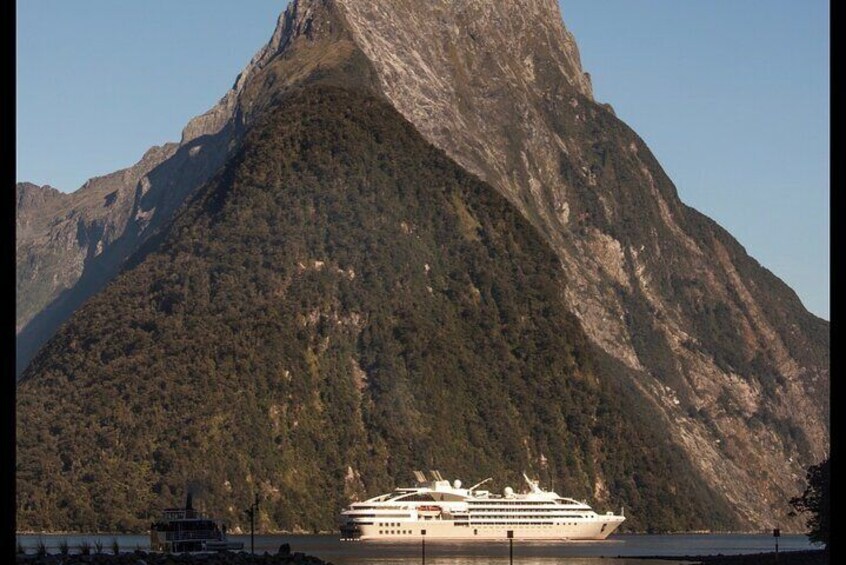 A cruise ship docked near a mountainous coastline. 2