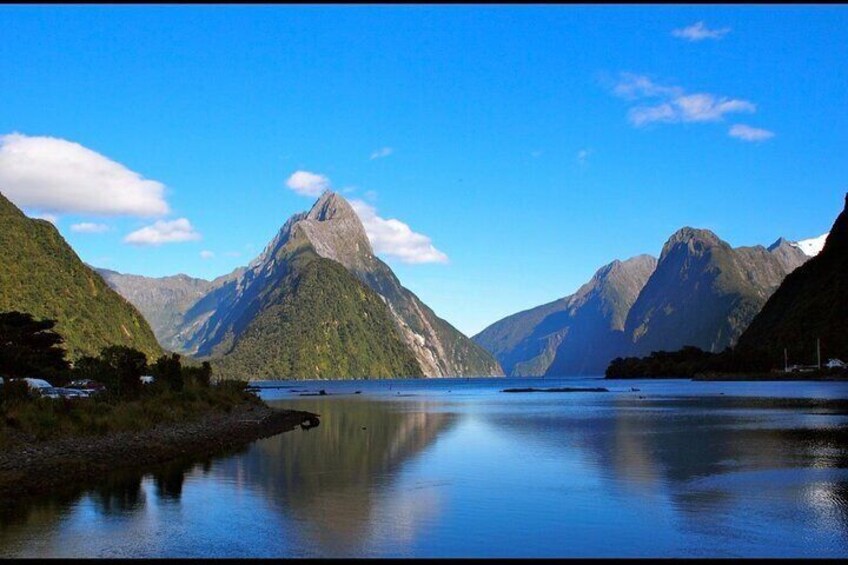 A calm lake surrounded by mountains with a clear sky. 1