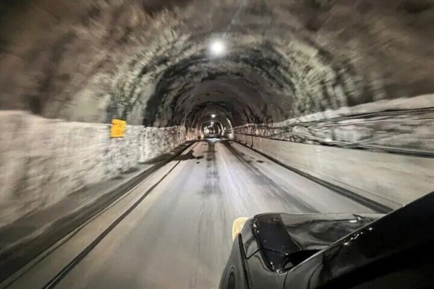 A car driving through a tunnel with a yellow sign on the left. 4