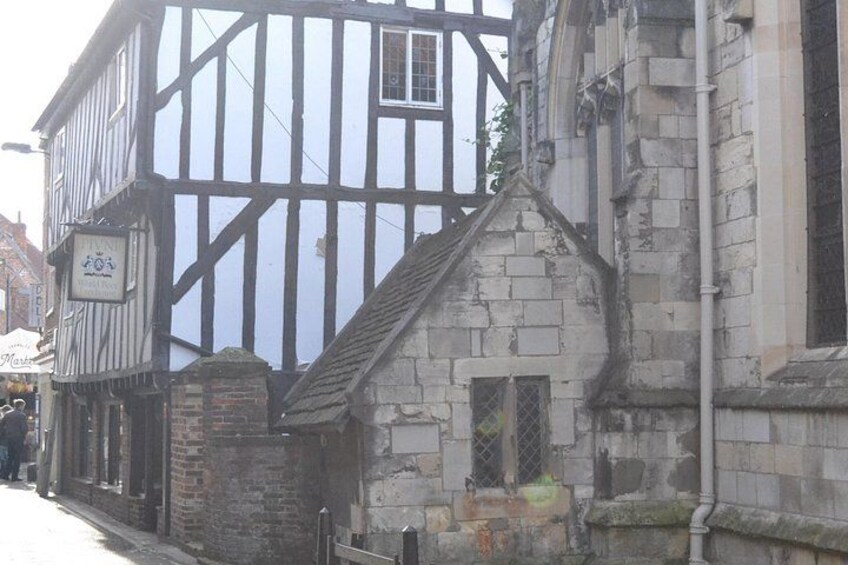 A half-timbered building with a stone structure adjacent to it. 2