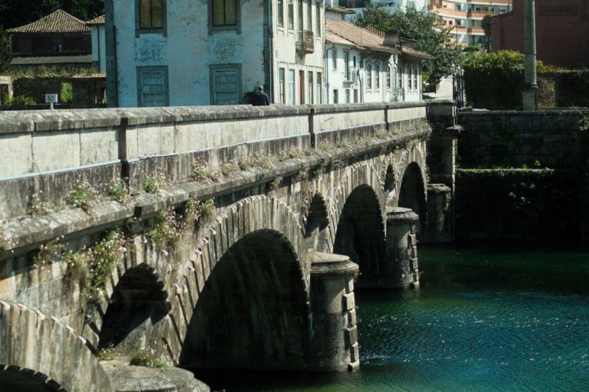 A stone bridge with arches over a body of water, surrounded by buildings. 2