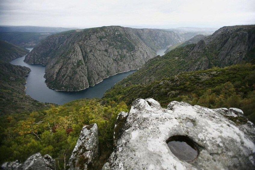 A canyon with a river, rocky terrain, and a prominent rock with a hole. 5