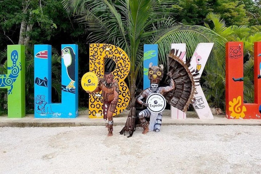 Colorful letters with animal designs, a person in a costume, and a shield with a logo. 2