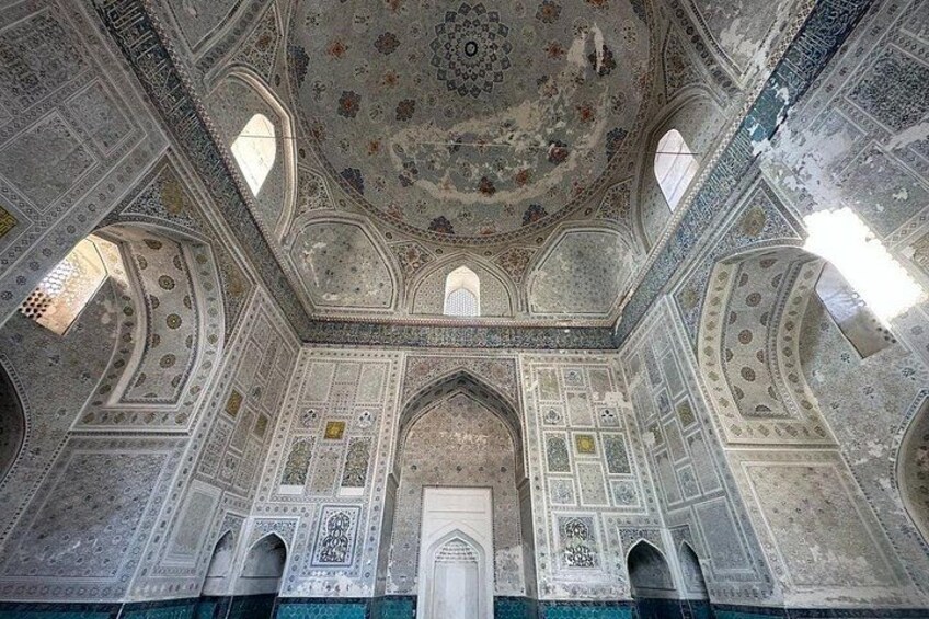 An ornate interior with detailed ceiling patterns, arched doorways, and a central dome. 5