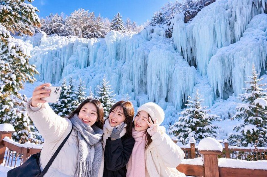 A group of people taking a selfie with a frozen waterfall in the background. 5