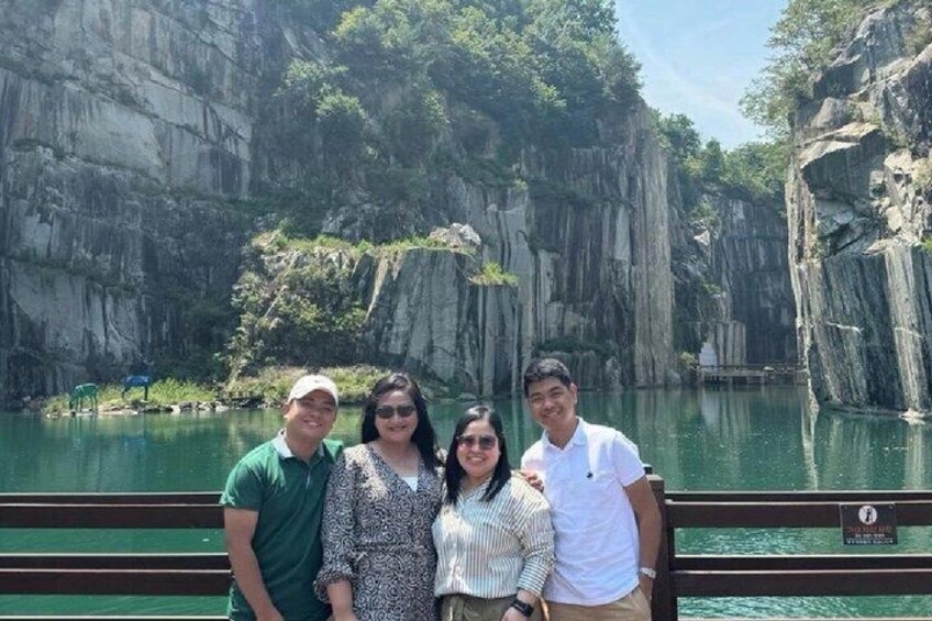 A group of people on a boat near a rocky cliff and a calm body of water. 5