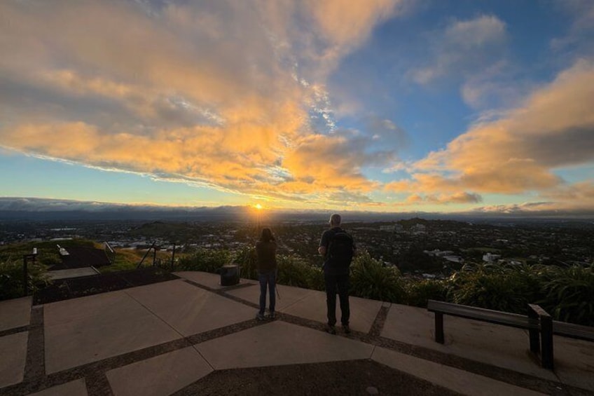 Dos personas en un área pavimentada observando un paisaje urbano al atardecer. 3