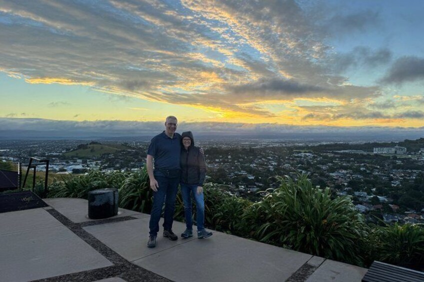 Una pareja parada en una terraza con vista a un paisaje urbano al atardecer. 4