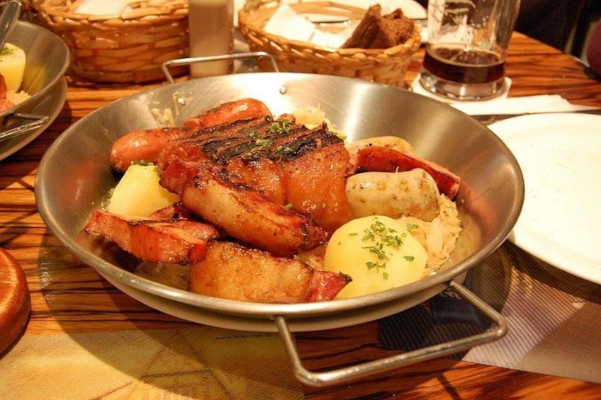 A pan with roasted meat, potatoes, and a garnish. 2