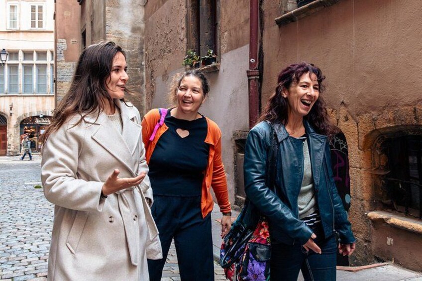 Three people walking on a cobblestone street in an urban setting. 3
