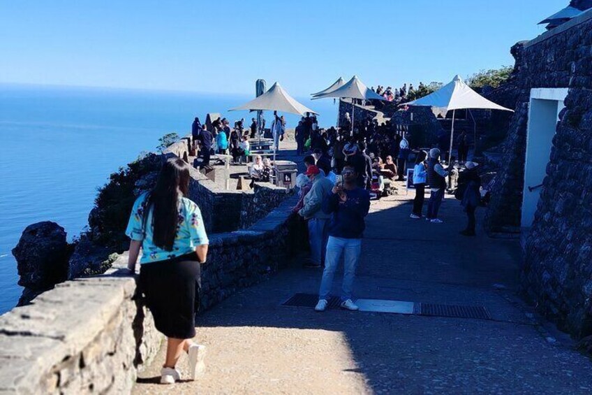 A coastal walkway with people walking and sitting under umbrellas. 2