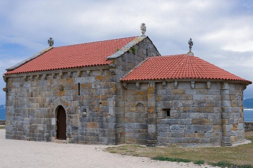 A stone building with a red-tiled roof and a small arched entrance. 3