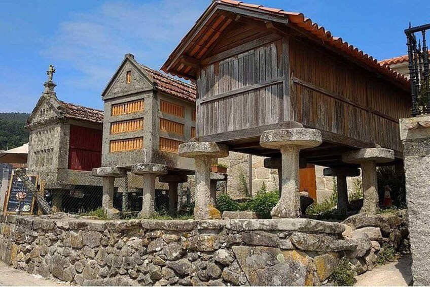 A traditional wooden house with a stone foundation, a stone wall, and a small building with a red door. 4