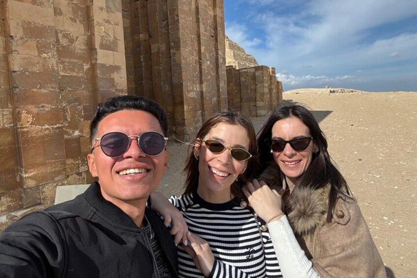 Three people taking a selfie in front of an ancient Egyptian structure with a desert landscape in the background. 3