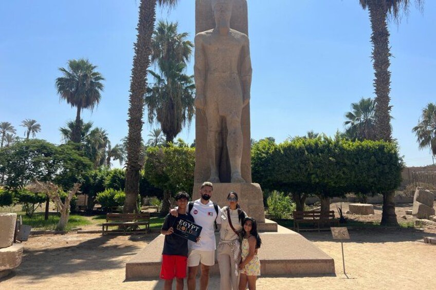 A large statue of a pharaoh, palm trees, and a clear sky. 5