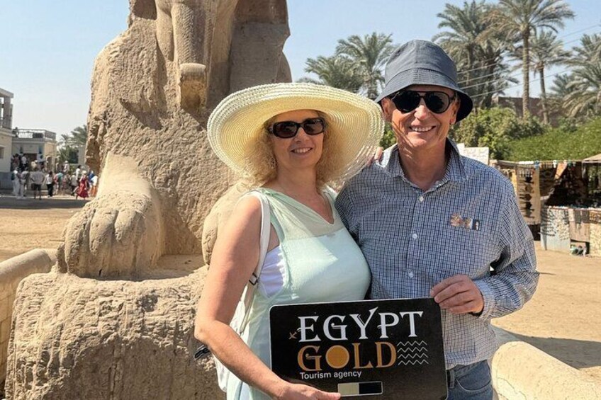 A large stone statue, a person holding a sign that reads 'EGYPT GOLD,' and palm trees in the background. 2